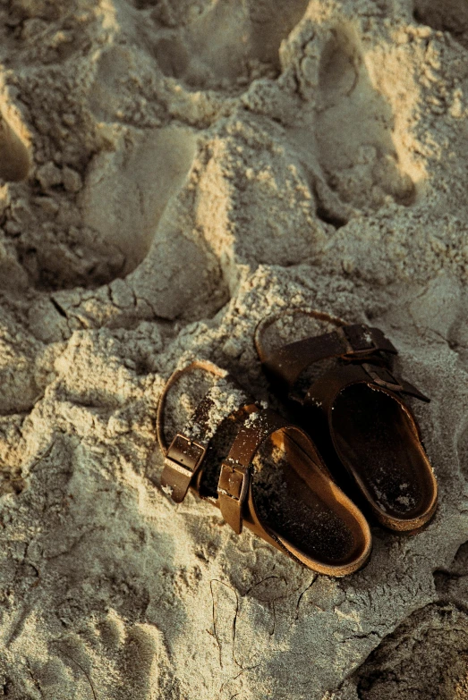 a pair of shoes sitting on top of a sandy beach, birkenstock sandals, the ground is dark and cracked, harsh sunlight, multiple stories