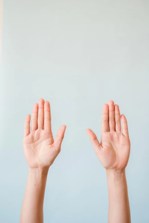 a person holding their hands up in the air, trending on pexels, plain background, facing each other, no ears, palm lines