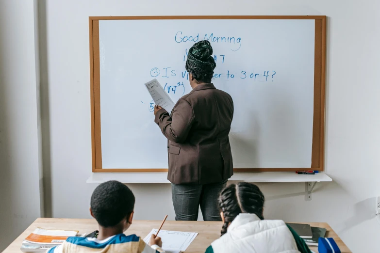 a woman standing in front of a whiteboard with writing on it, by Carey Morris, pexels contest winner, ashcan school, sitting in the classroom, morning time, background image