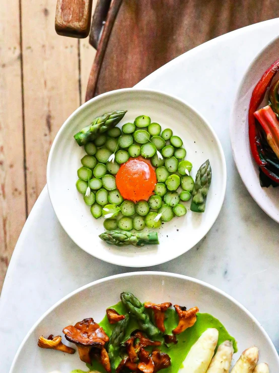 a table topped with plates of food on top of a wooden table, asparagus, red caviar instead of sand, spiraling, pickle