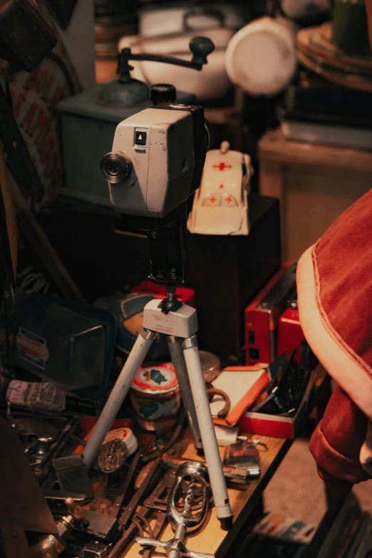 a camera sitting on top of a wooden table, a still life, inspired by Elsa Bleda, vhs artefacts, inspect in inventory image, cinemascope panorama, cluttered room