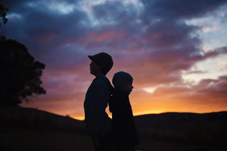 a man holding a baby in his arms at sunset, by Jessie Algie, unsplash contest winner, silhouette :7, younger brother vibes, lachlan bailey, dark sky