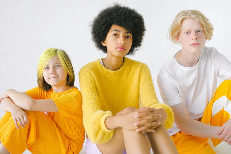 a group of young women sitting next to each other, by Ellen Gallagher, pexels, antipodeans, white and yellow scheme, different hair colours, yellow clothes, nina tryggvadottir