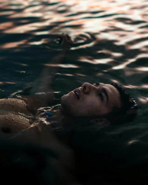 a man floating in a body of water, inspired by Elsa Bleda, trending on unsplash, happening, non binary model, in the evening, mid-shot of a hunky, concerned