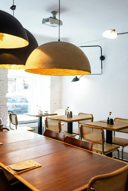 a dining room filled with wooden tables and chairs, inspired by Barthélemy Menn, unsplash, street corner, clamp shell lighting, clean lighting, cozy environment