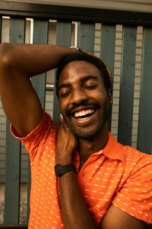 a man in an orange shirt talking on a cell phone, by Carey Morris, trending on unsplash, brown skin man with a giant grin, a portrait of rahul kohli, model posing, suspenders