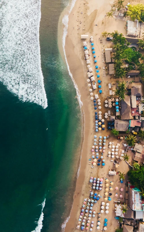 a beach filled with lots of umbrellas next to the ocean, pexels contest winner, helicopter view, beach bar, fishing village, lush surroundings