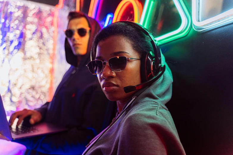 a woman sitting in front of a laptop wearing headphones, a portrait, pexels, graffiti, riot games, wear ray - ban glass, medium shot of two characters, black halo