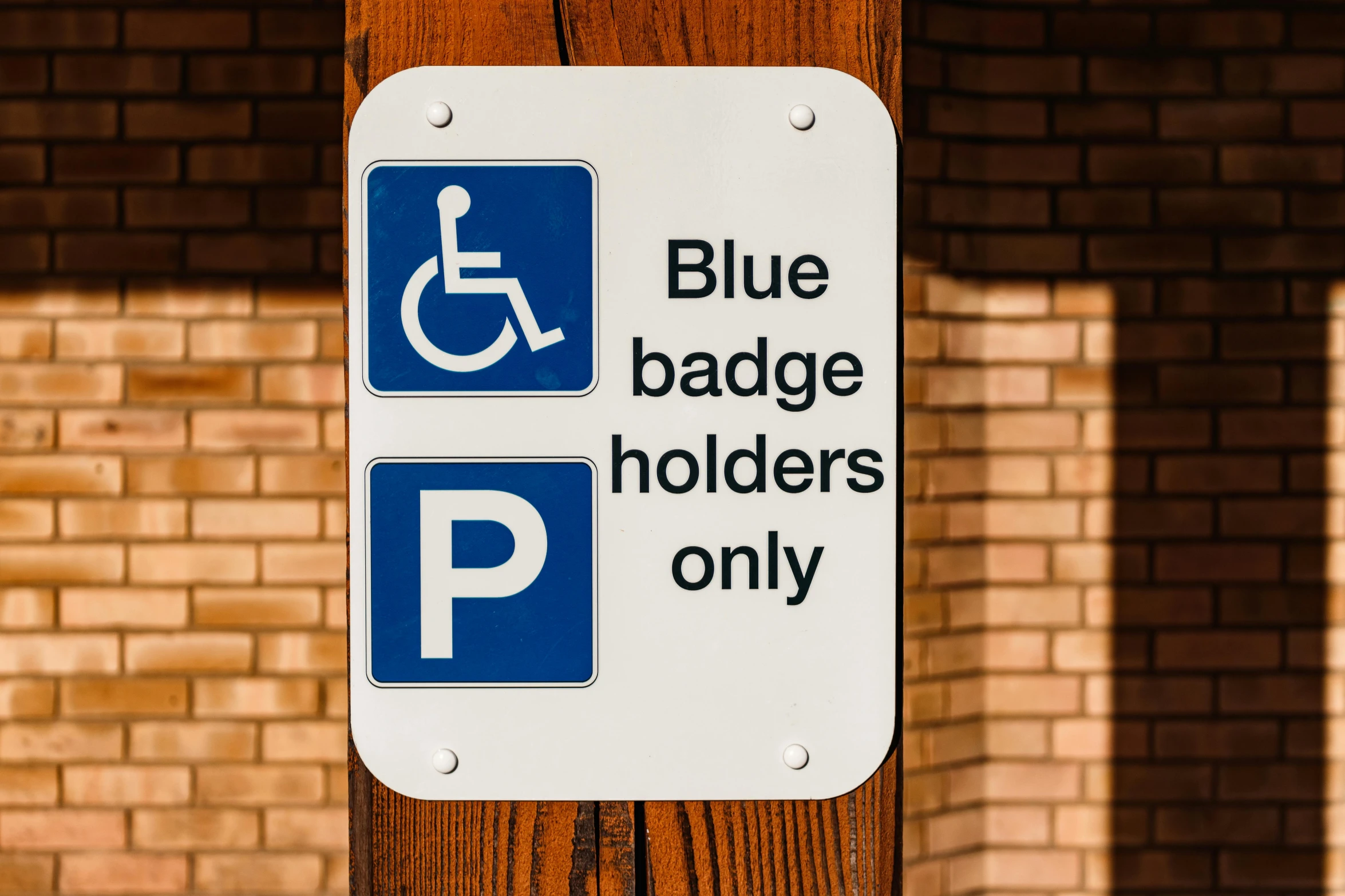 a blue and white sign on a wooden pole, by Julia Pishtar, pexels, sitting in a wheelchair, badge, square, blue: 0.5