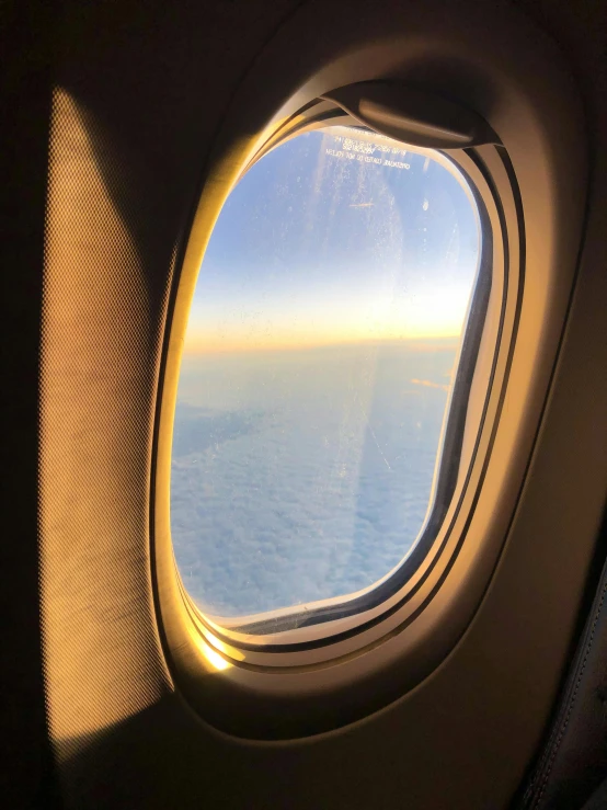 an airplane window with a view of the ocean, a picture, lit from above, airing in 2 0 2 3, early morning sun in the sky, flitting around in the sky