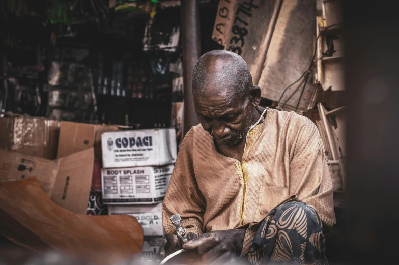 a man is working on a piece of wood, by Will Ellis, pexels contest winner, afrofuturism, old man, market, yoruba body paint, sitting in his chair. intricate