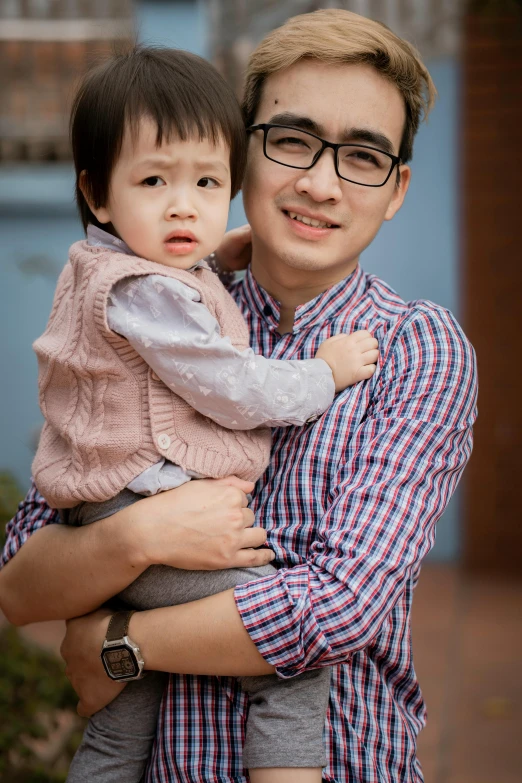 a man holding a small child in his arms, a picture, by Reuben Tam, professional profile photo, square, wearing casual clothing, li zixin