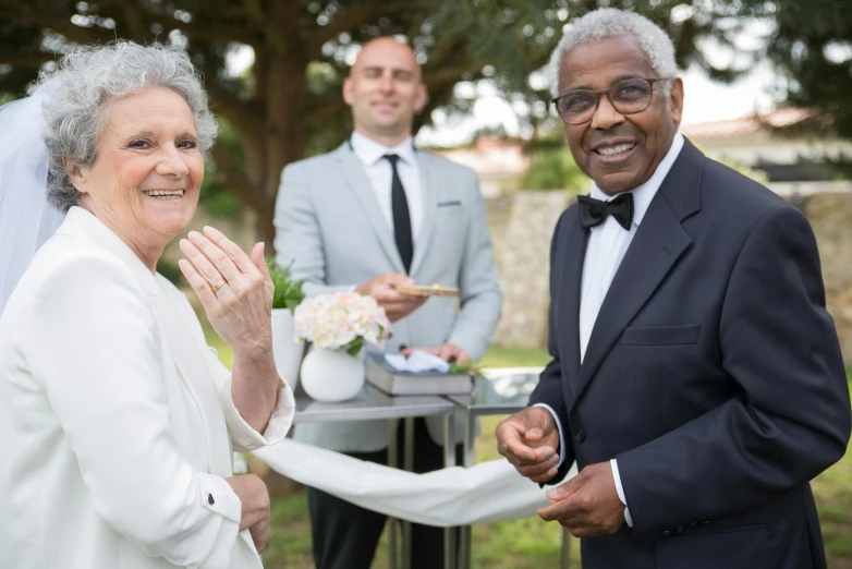 a man putting a wedding ring on a woman's finger, pexels contest winner, renaissance, two aboriginal elders, wearing a white tuxedo, smiling for the camera, al fresco