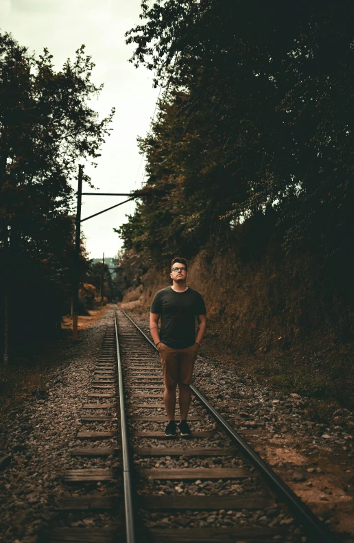 a man is standing on a train track, a picture, pexels contest winner, plain background, mid body portrait, structure : kyle lambert, vsco film grain