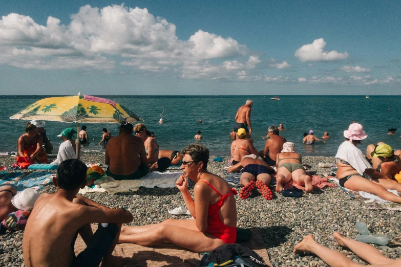 a group of people sitting on top of a beach, crowded people, martin parr, unsplash photography, wearing a white bathing cap