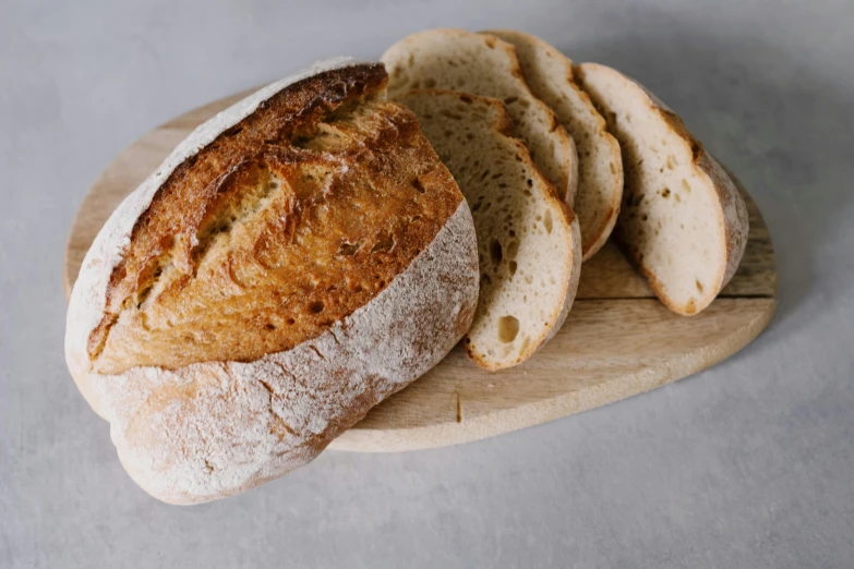 a loaf of bread sitting on top of a wooden cutting board, by Tom Bonson, pexels, fan favorite, white, rice, sandstone