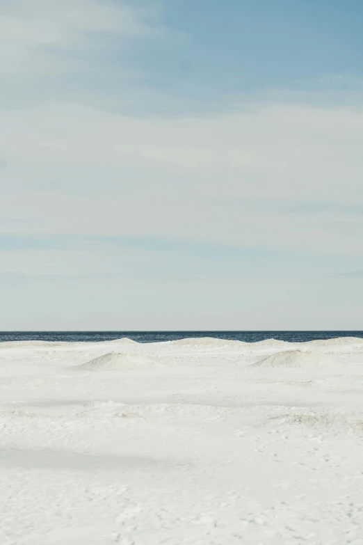 a man riding a snowboard down the side of a snow covered slope, by Alison Geissler, minimalism, ocean shoreline on the horizon, michigan, ignant, sand sea