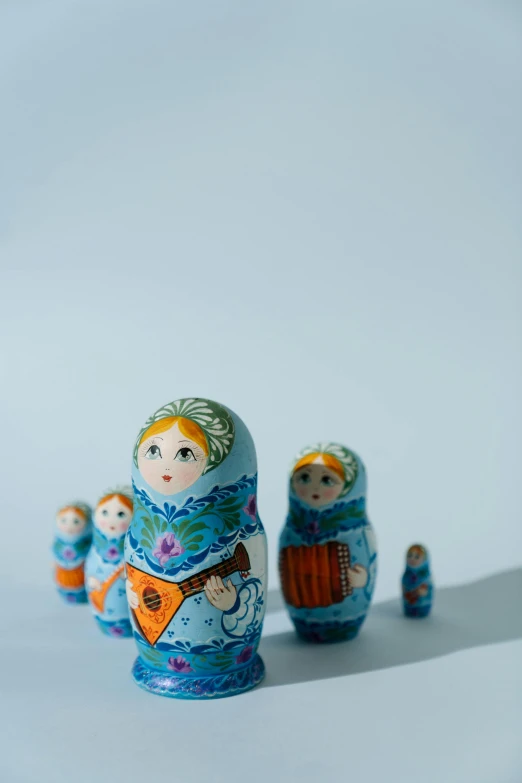 a group of russian nesting dolls on a white surface, an album cover, by artist, unsplash, folk art, blue!! with orange details, made of silk paper, high resolution product photo, made of glazed