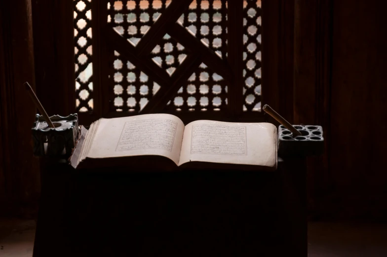 an open book sitting on top of a table, hurufiyya, in front of a carved screen, the best, in a sanctuary, well edited