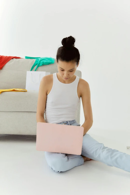 a woman sitting on the floor with a laptop, pastel clothing, wearing a cropped tops, playing, no text