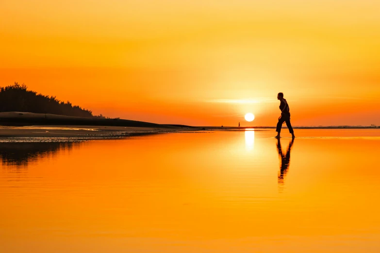 a person walking on a beach at sunset, pexels contest winner, on a reflective gold plate, vibrant orange, walking boy, heat shimmering