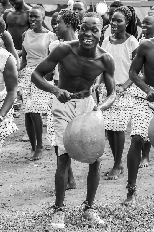 a black and white photo of a group of people playing with a ball, by Ingrida Kadaka, african man, holding helmet, dancing character, ( ( photograph ) )