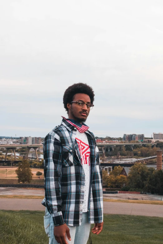 a man standing on top of a lush green field, an album cover, by Washington Allston, unsplash, visual art, cityscape, wearing a flannel shirt, ((portrait)), afro