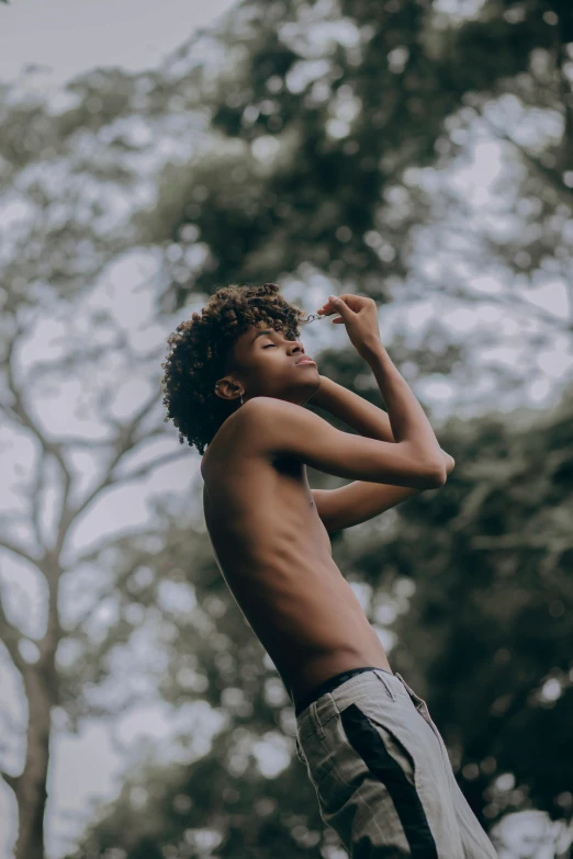 a young man standing on top of a skateboard, by Maxwell Bates, pexels contest winner, visual art, afro hair, against the backdrop of trees, bare shoulders, profile pic