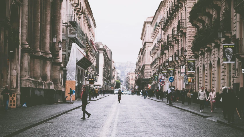 a man riding a bike down a street next to tall buildings, by Anita Malfatti, pexels contest winner, neoclassicism, naples, people walking down a street, empty road in the middle, a blond