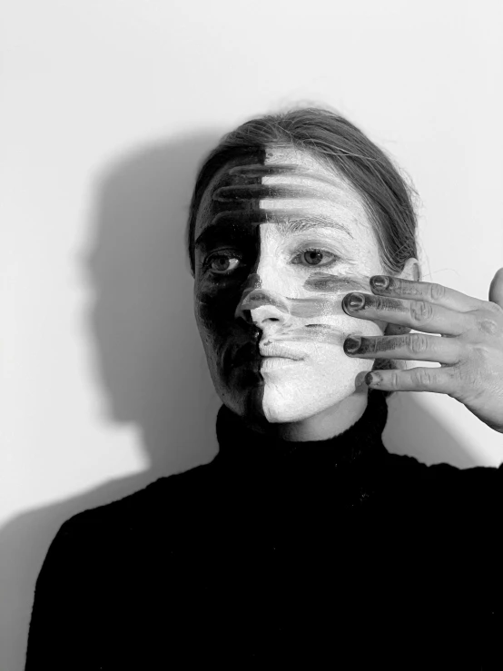 a black and white photo of a woman covering her face with her hands, a black and white photo, inspired by Anna Füssli, facepaint, image split in half, cast shadows, half and half