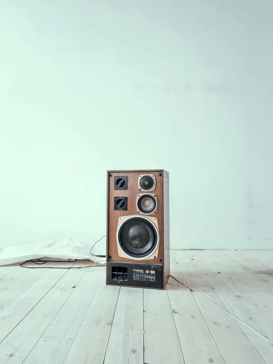 a speaker sitting on top of a wooden floor, an album cover, trending on unsplash, hyperrealism, 7 0 s hi fi system, set against a white background, in a cinematic wallpaper, on an empty stage from above