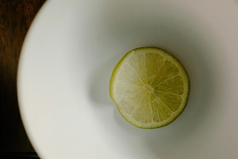 a slice of lime in a white bowl, inspired by Grillo Demo, trending on unsplash, porcelain organic tissue, ignant, lemon, round-cropped