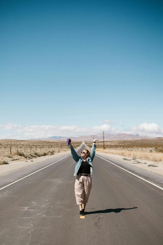 a woman standing on the side of a road with her arms in the air, desert!!!, hands in pockets, waving and smiling, oh the places you'll go