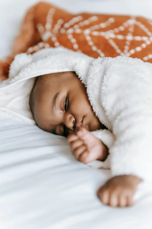 a baby wrapped in a blanket laying on a bed, pexels contest winner, brown skinned, sleeping beauty, thumbnail, wearing white pajamas