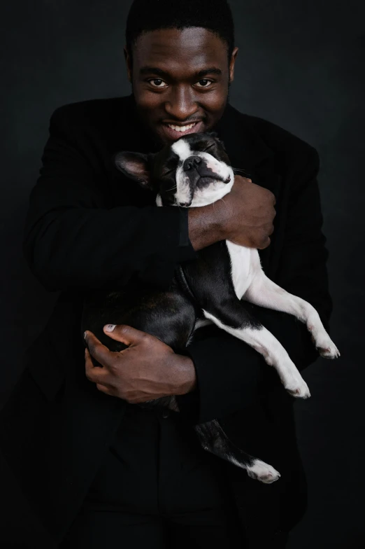a man in a suit holding a small dog, an album cover, pexels contest winner, ( ( dark skin ) ), french bulldog, ivory and ebony, black
