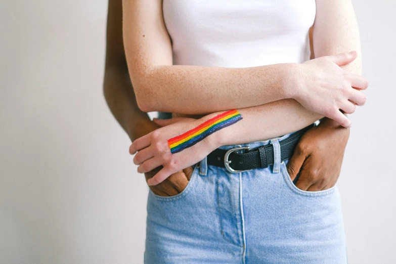 a woman with a rainbow painted on her arm, by Nina Hamnett, trending on pexels, renaissance, two men hugging, wearing jeans, striped, diverse