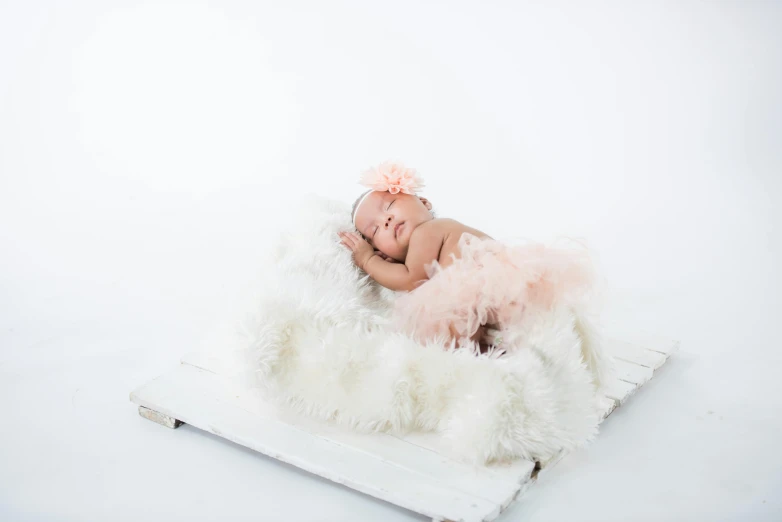 a baby sleeping on top of a white blanket, an album cover, by Will Ellis, shutterstock contest winner, pink tutu, full body photoshoot, soft feather, small