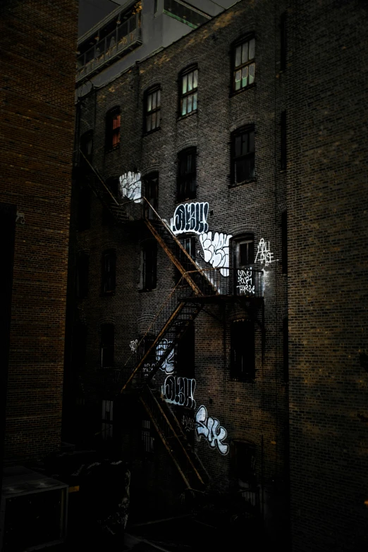 a building with graffiti on the side of it, inspired by Elsa Bleda, pexels contest winner, stairways, dark shadowy surroundings, location [ chicago ( alley ) ], fire escapes
