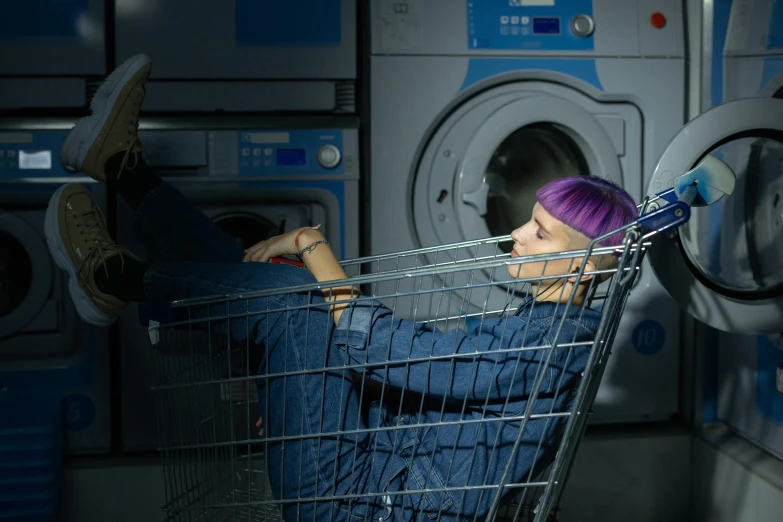 a woman sitting in a shopping cart in front of a washing machine, inspired by Elsa Bleda, pexels contest winner, die antwoord ( yolandi visser ), purple, capsule hotel, fatigue