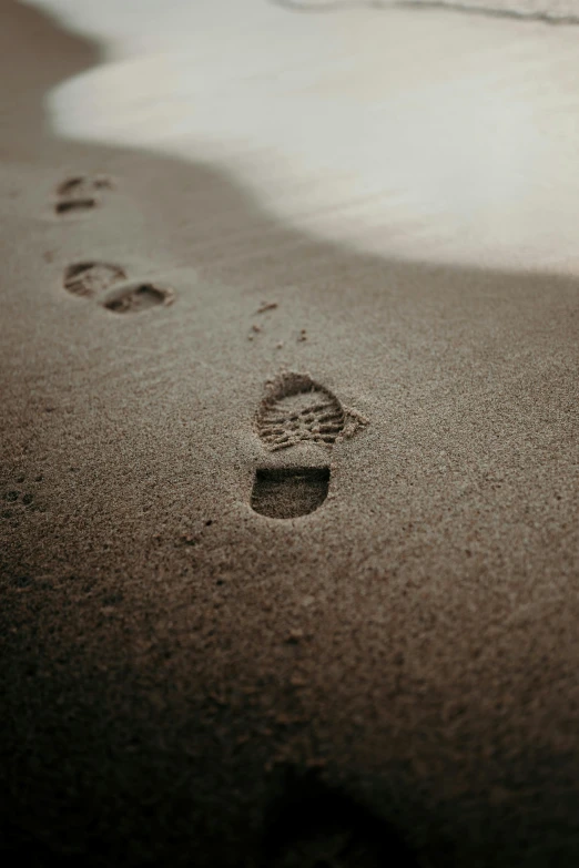 a couple of footprints that are in the sand, an album cover, pexels, 10k, staggered depth), brown, low light