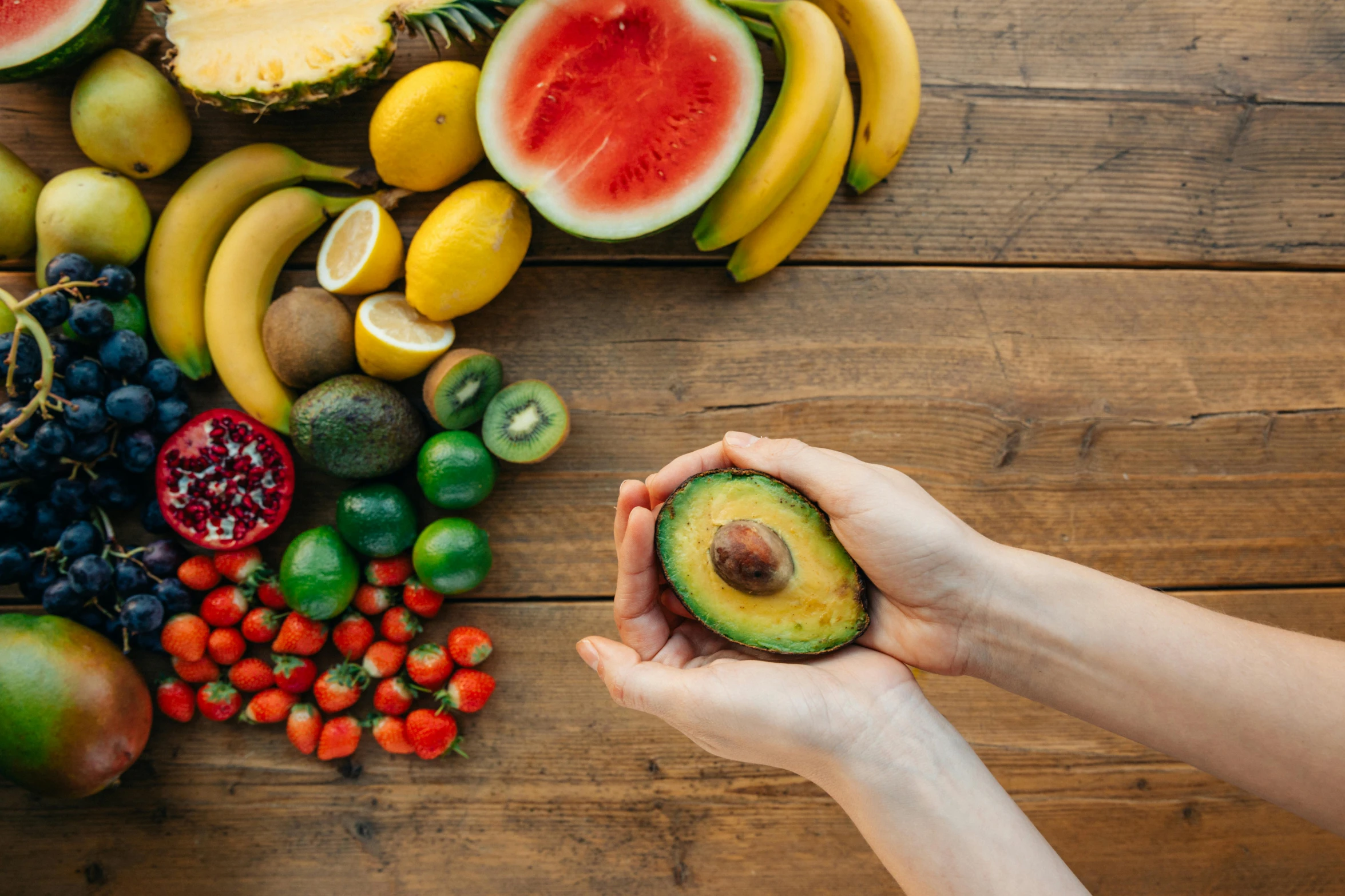 a person holding an avocado in front of a variety of fruits, trending on pexels, avatar image, background image, ingredients on the table, film photo