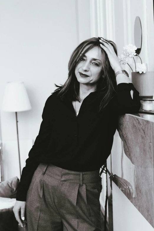 a black and white photo of a woman leaning against a wall, a black and white photo, maria panfilova, sitting in a lounge, wearing a designer top, desaturated