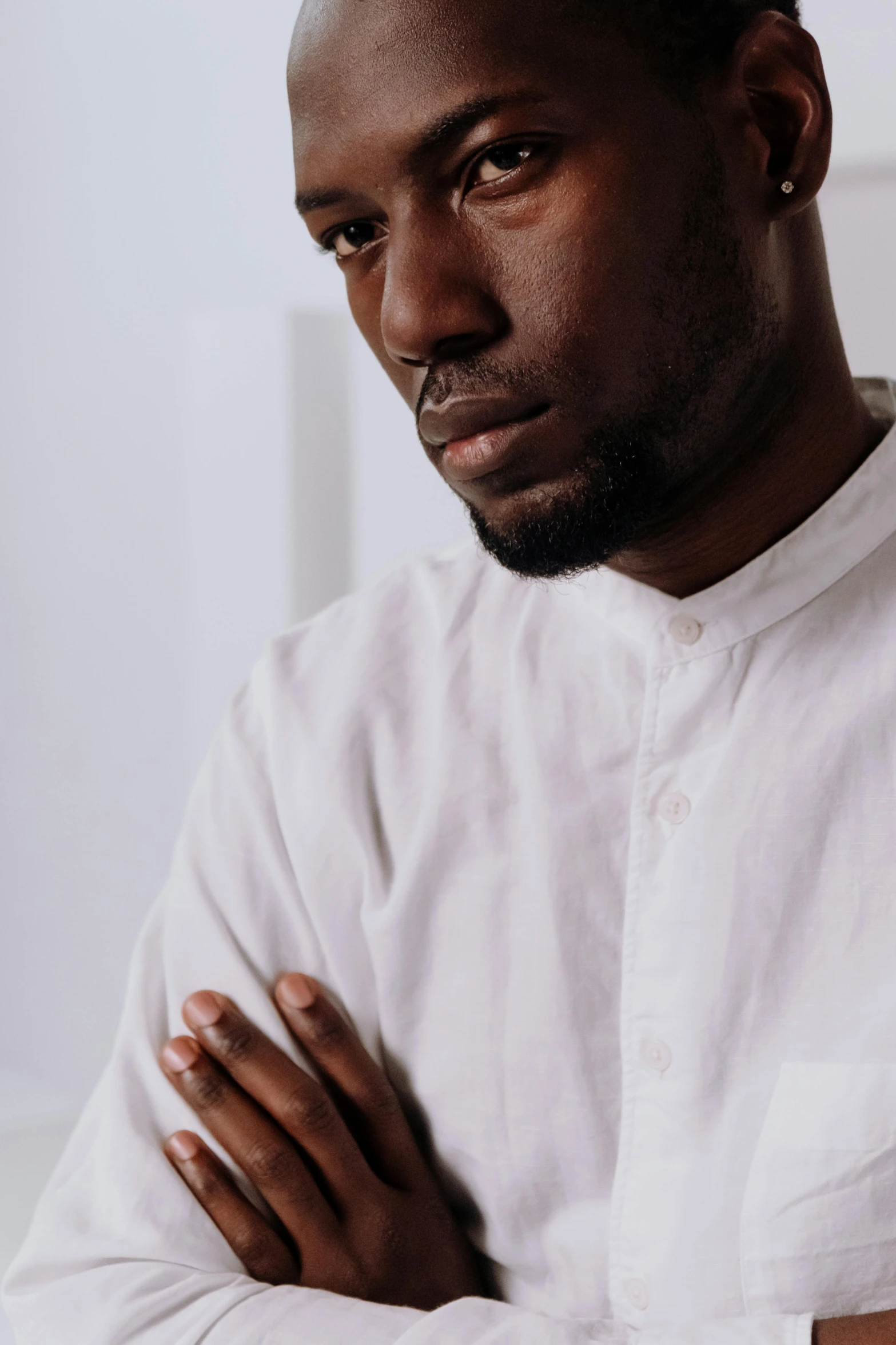 a man in a white shirt with his arms crossed, a character portrait, inspired by Theo Constanté, trending on pexels, riyahd cassiem, contemplative, kano), sitting on man's fingertip