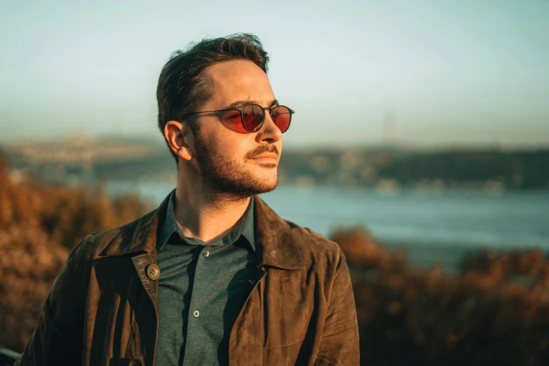 a man standing in front of a body of water, red sunglasses, avatar image, afternoon lighting, profile image