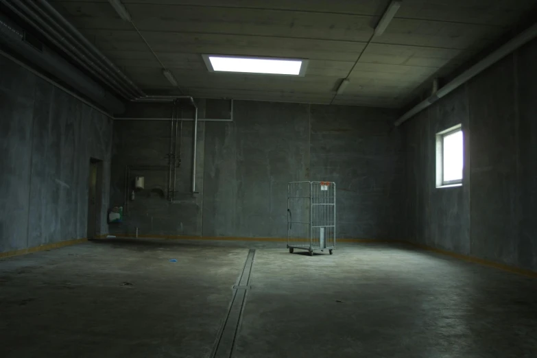 a room with a cart in the middle of it, inspired by Thomas Struth, unsplash, light and space, dark concrete room, maintenance area, experimental studio light, an escape room in a small