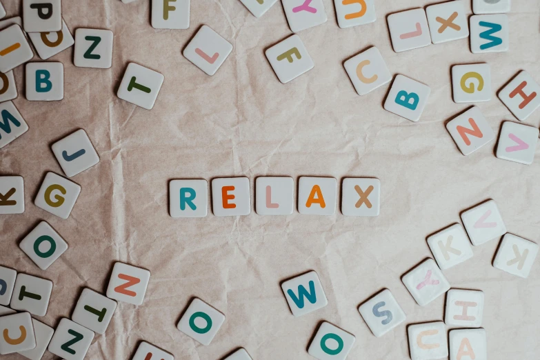 a pile of scrabbles sitting on top of a table, a mosaic, trending on pexels, relax, background image, laying back on a pillow, flowing lettering