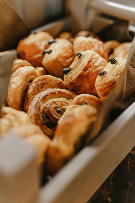 a tray of croissants sitting on top of a counter, snails, radiant soft light, thumbnail, chocolate