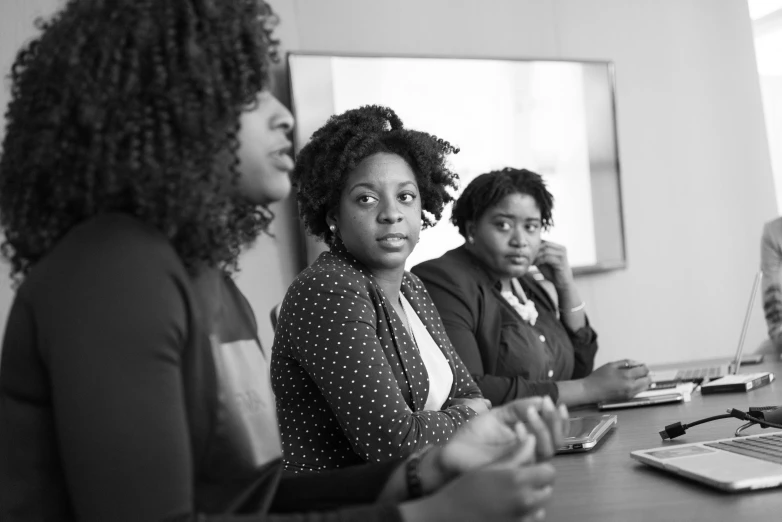 a group of women sitting around a wooden table, pexels, realism, african american woman, in a meeting room, bw, three women