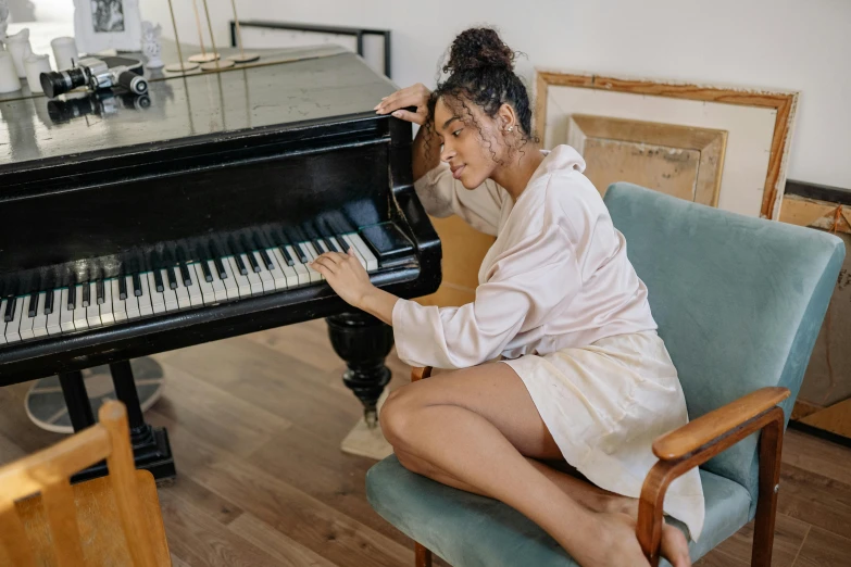 a woman sitting on a chair playing a piano, pexels contest winner, sleepy feeling, wearing a camisole and shorts, wearing a tracksuit, french provincial furniture