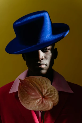 a man wearing a blue hat and holding a lollipop, an album cover, inspired by Paul Georges, pexels contest winner, afrofuturism, horst p. horst, innocent look. rich vivid colors, delicate androgynous prince, beans